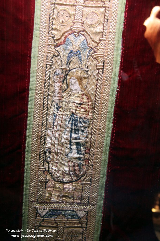 Embroidered goldwork orphrey on a red late medieval vestments.