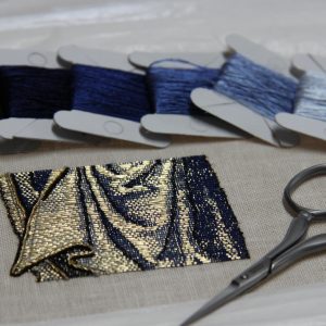 Goldwork embroidery sample with bobbins with silk and scissors.