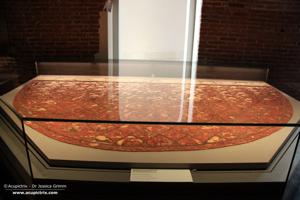 Italian embroidery - A large red cope laying flat in a museum display case