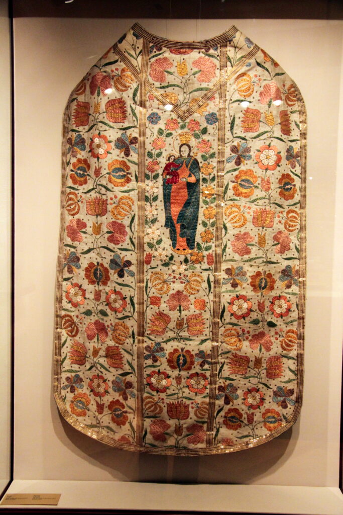 Linen Vestments Tyrol - an embroidered chasuble displayed in a glass case