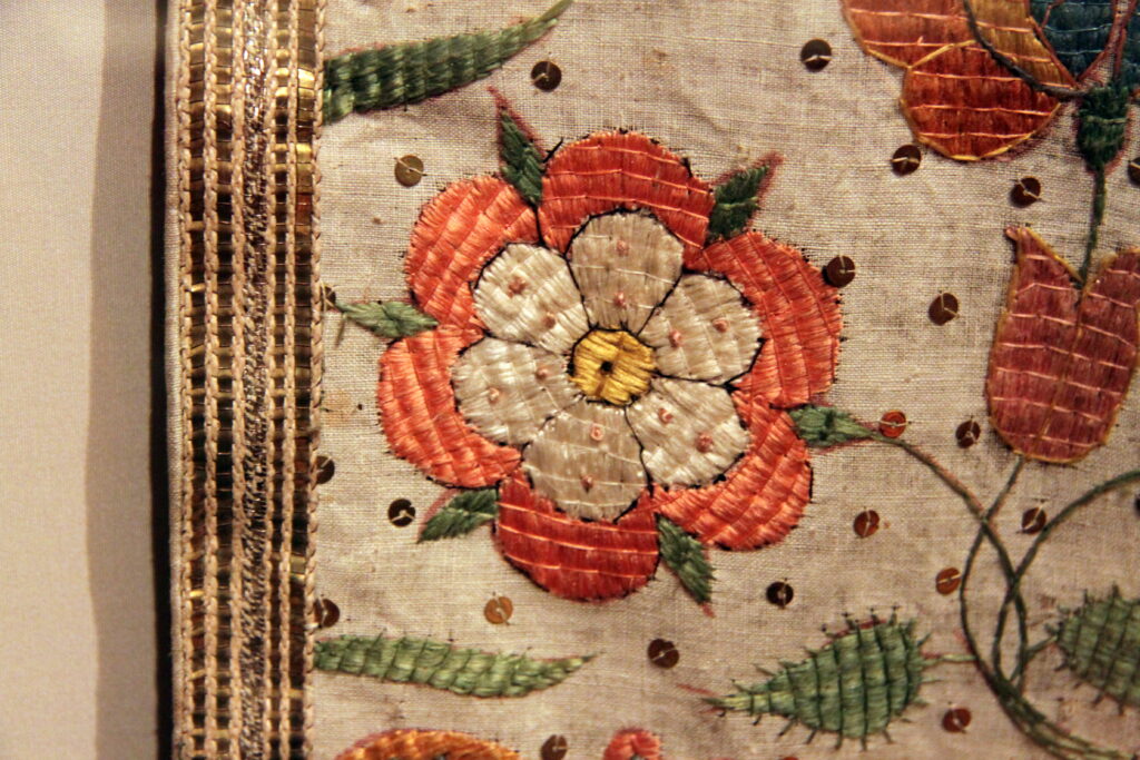 Linen Vestments Tyrol - an embroidered chasuble displayed in a glass case
