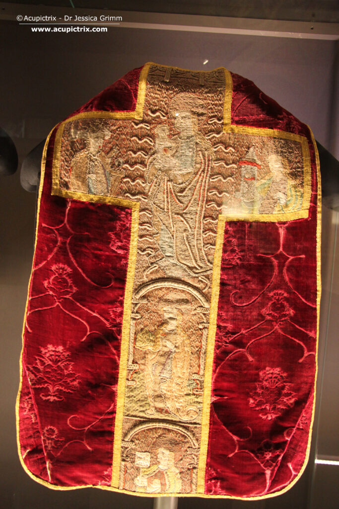 Medieval goldwork - multicoloured embroidered cross on a red chasuble