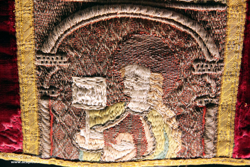 Medieval goldwork - multicoloured embroidered cross on a red chasuble