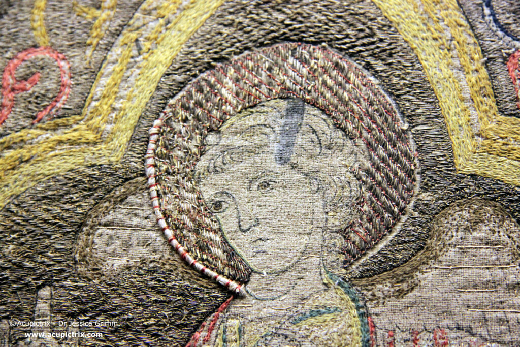Opus romanum - multi coloured embroidery showing the nimbed head of an angel