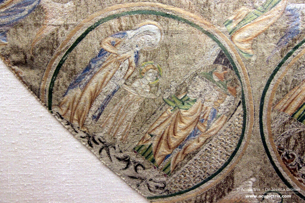 Opus anglicanum - multi coloured embroidery showing a woman, a boy and several men
